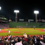 a baseball game in a stadium with Fenway Park in the background