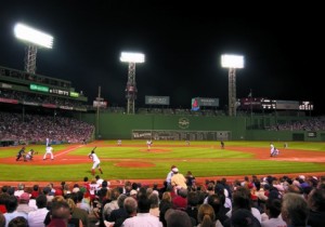 a baseball game at night with Fenway Park in the background