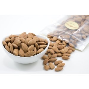 a bowl of almonds next to a bag of nuts