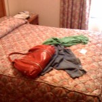 a red purse and clothes on a bed
