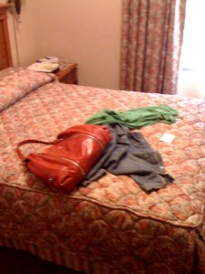 a red purse and clothes on a bed