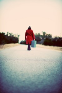 a woman in a red coat carrying a suitcase