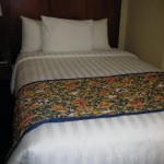 a bed with white pillows and a floral blanket