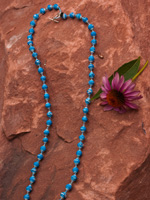 a blue beaded necklace and a purple flower