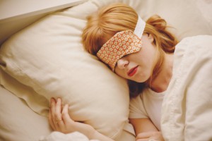 a woman sleeping in bed with a blindfold