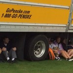 a group of people sitting under a truck