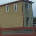 a yellow house with a red fence