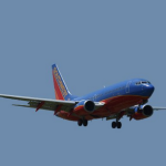 a blue and red airplane flying in the sky