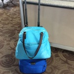 a blue bag on top of a suitcase