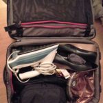 a suitcase with a iron and shoes inside